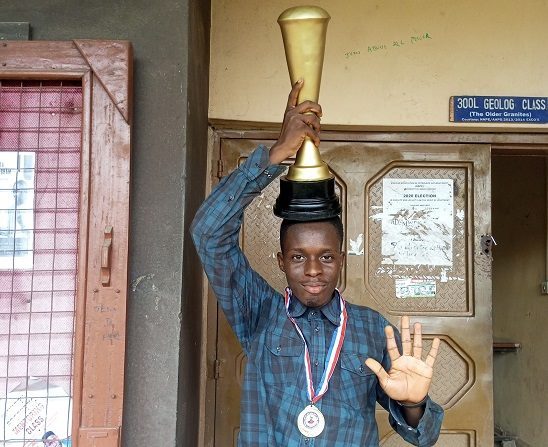 Holding a trophy overhead in front of the geology department door