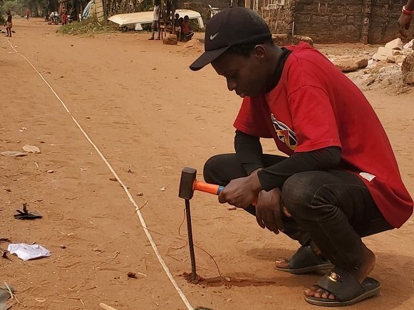 Driving an electrode into the ground with a hammer during a survey