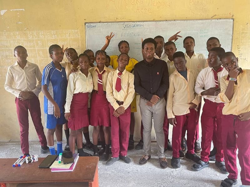 A class of secondary school students standing together in a classroom
