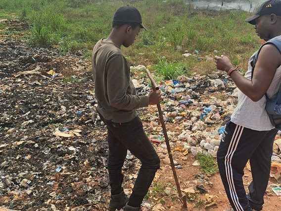 Two people collecting samples at a dumpsite